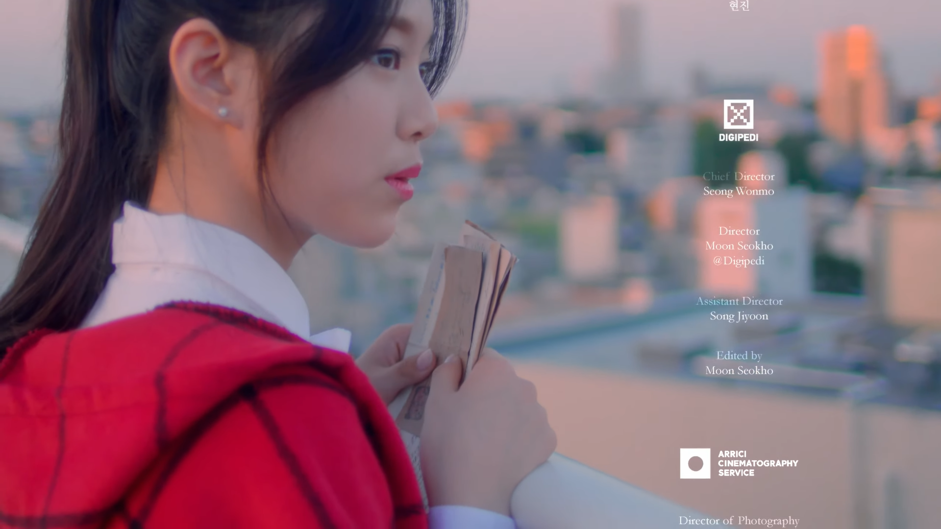 Hyunjin holding the letters with a cityscape behind her.